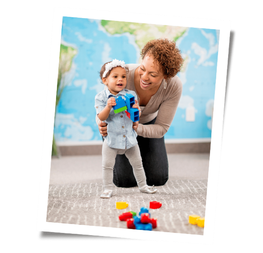 A mother joyfully watches her toddler build with colorful blocks in a playroom adorned with a world map background, grateful for the help of a trusted San Francisco nanny agency.